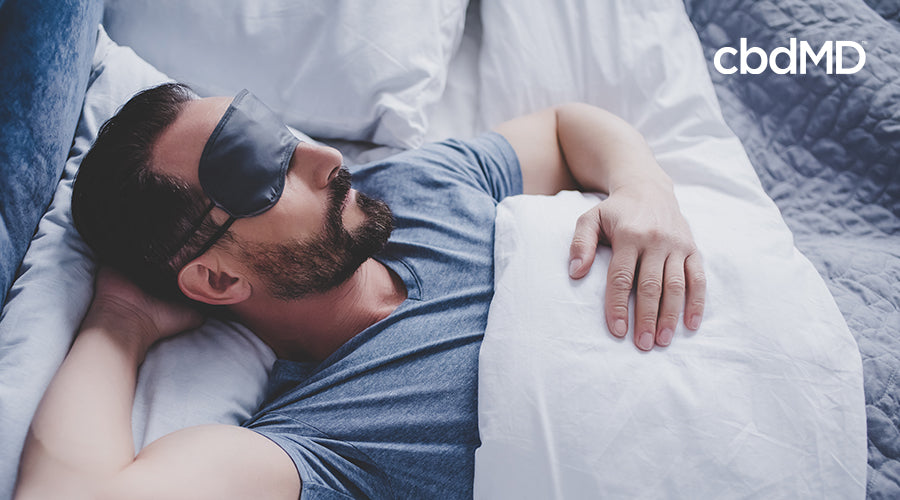 A man sleeping in a bed with a night mask on