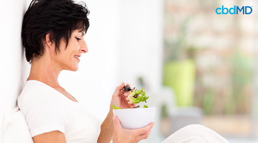 A woman sitting down eating salad out of a bowel