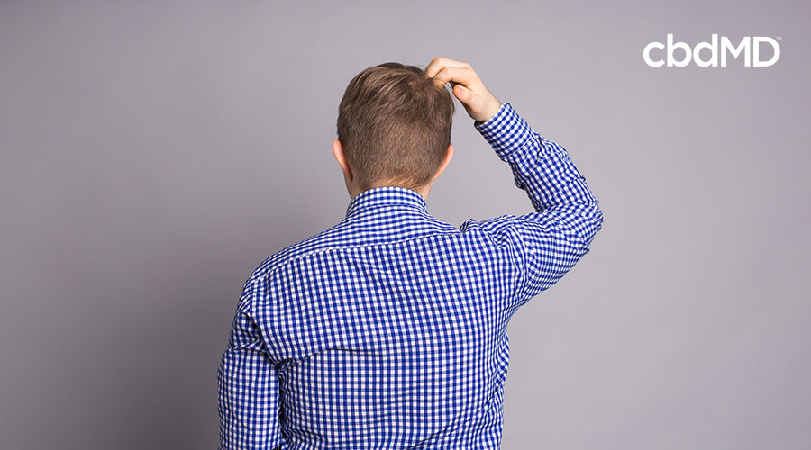 A man scratching his head with his hand