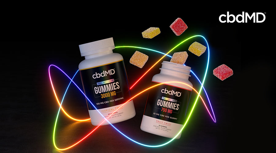 cbdMD full spectrum gummies 3000 mg tropical twist and 750 mg fruit twist bottles next to each other with gummies coming out of one of the bottles with a light pattern around it