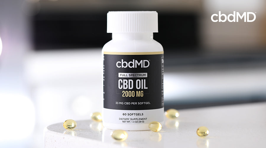 cbdMD full spectrum cbd oil 2000mg bottle with softgels laying around it on a table
