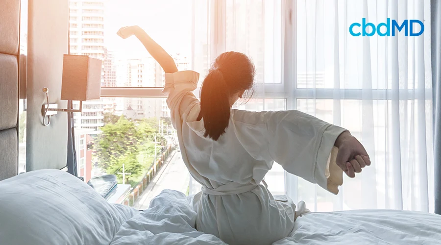 A woman waking up and stretching on her bed.