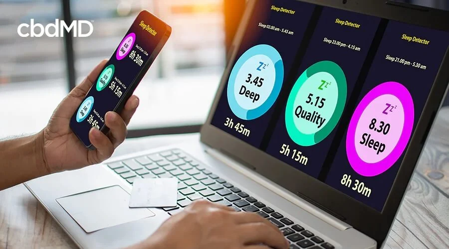 Someone holding a phone and looking at a desktop monitor with a sleep app that displays deep quality and overall sleep