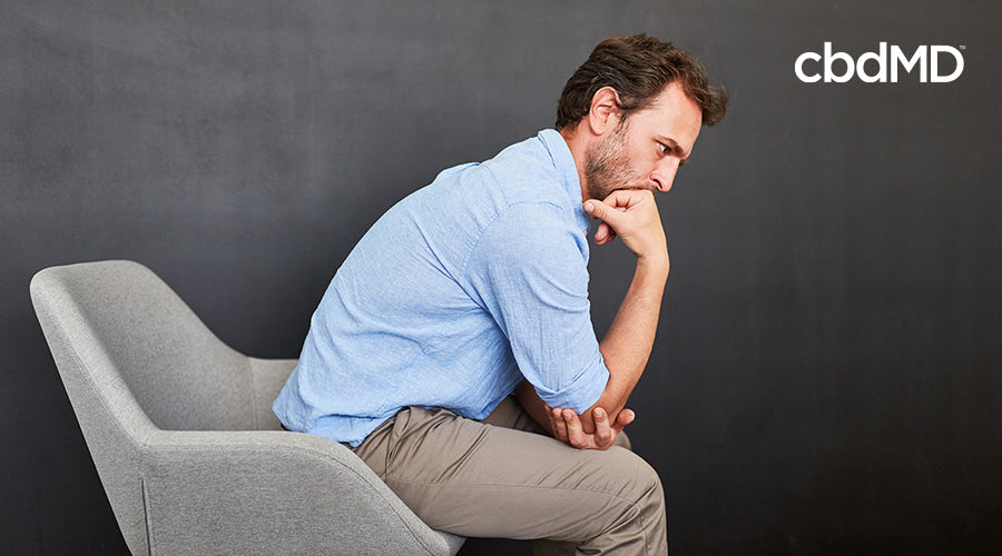 A man that is worried and thinking sitting in a chair