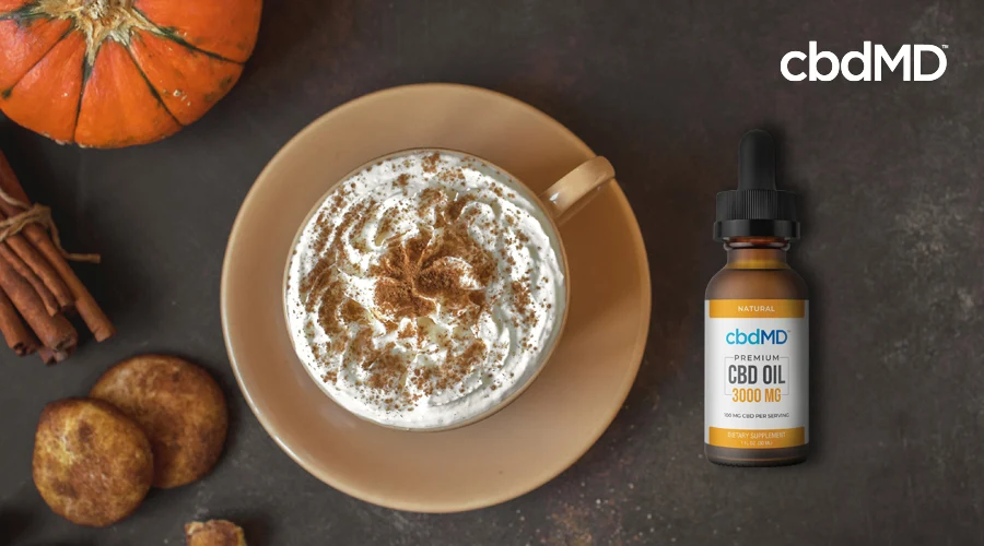 A mug with cbd pumpkin spice latte in it with a bottle of cbdMD cbd oil natural 3000mg next to it