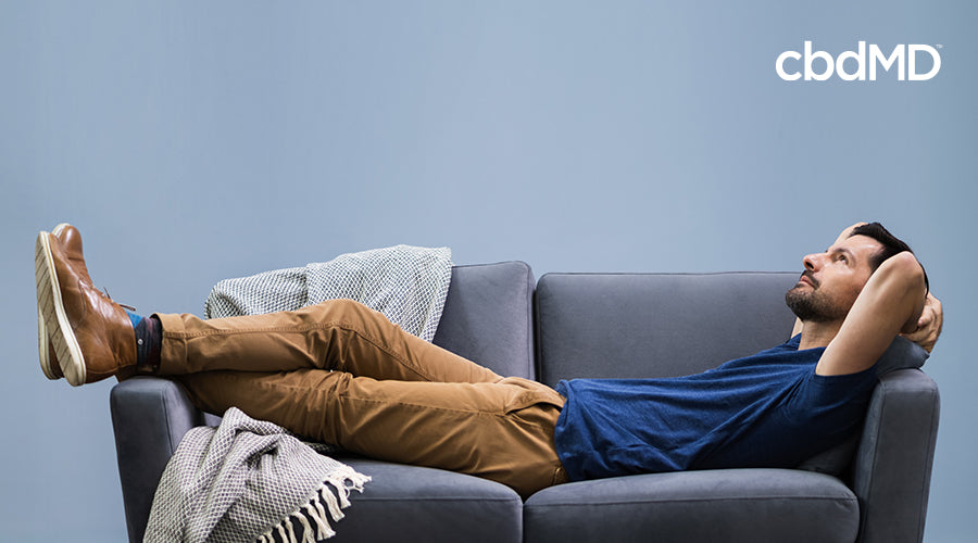 A man relaxing on a couch laying on his back looking up