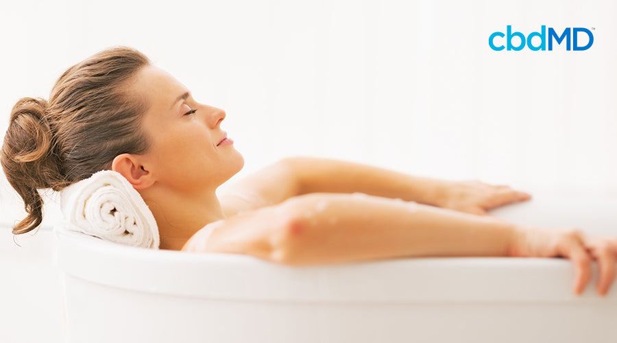 A woman laying in a bath with her head rested on a towel