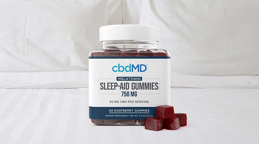cbdMD melatonin sleep aid gummies 750mg raspberry container laying on a bed