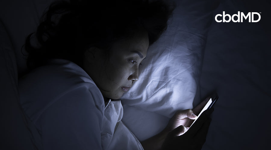 Woman with Phone in Bed