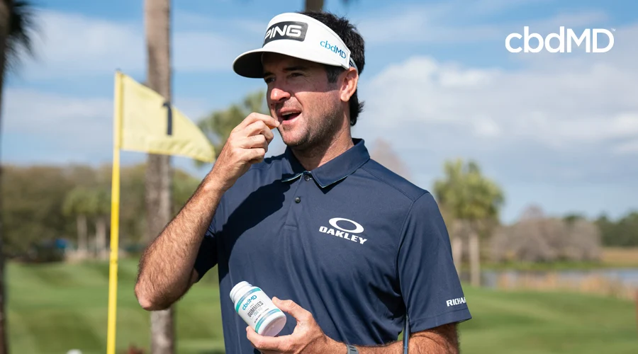 Two-time Masters champion Bubba Watson stands on golf course next to flag eating a 750 mg CBD gummy from cbdMD