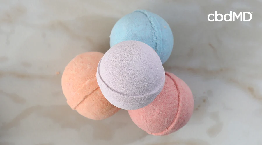 Pyramid stack of four CBD bath bombs by cbdMD including Rejuvenate, Rise, Romance, and Relax