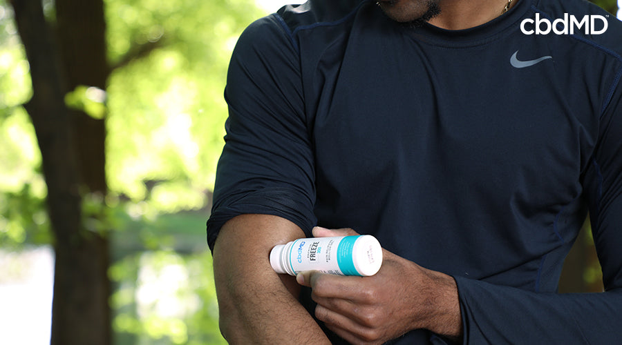 A man outside using premium freeze roll on for his arm - cbdMD
