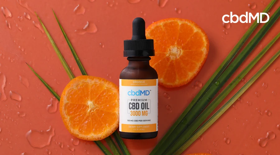 A bottle of 3000 mg cbd oil from cbdmd sits among orange slices and leaves