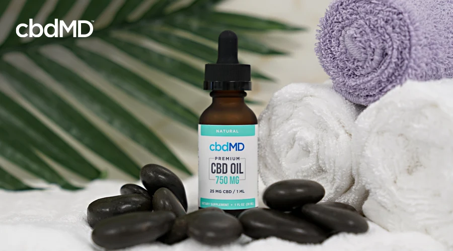 A 750 mg cbd oil tincture from cbdmd sits among some stones and rolled towels