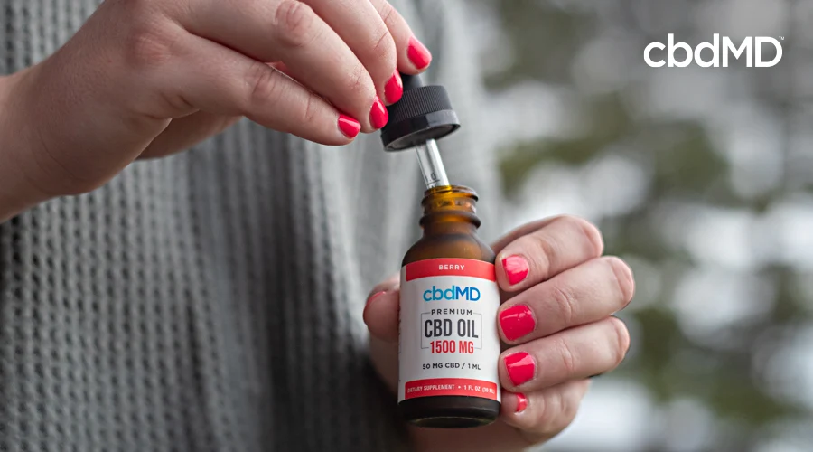 A woman with red painted nails pulls a dropper full of 1500 mg cbd tincture from cbdmd