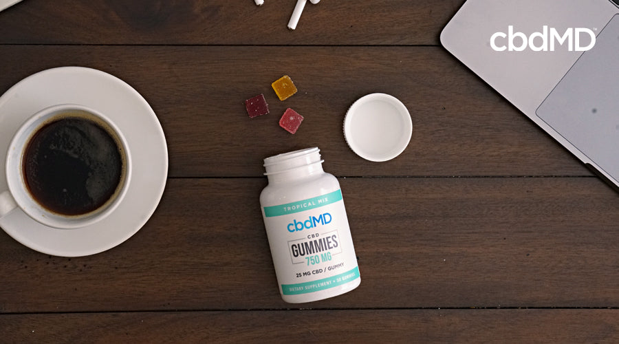An award winning bottle of cbd gummies from cbdmd lays on a desk with gummies spilling out
