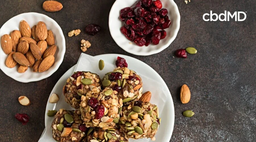 cbd berry healthy oatmeal bits sit on a plate surrounded by almonds and other fruit