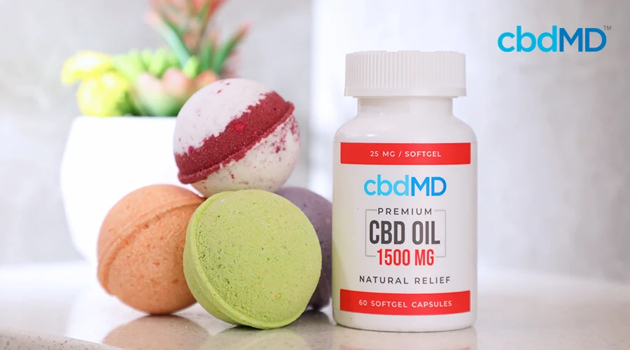 A bottle of 1500 mg cbd oil capsules from cbdmd sits next to a small stack of cbd bath bombs