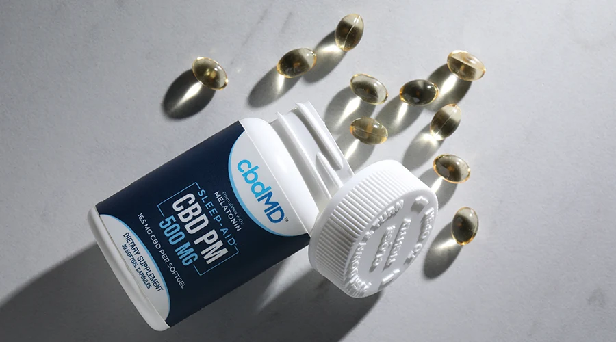 A bottle of 500 mg cbd sleep capsules from cbdmd lays on its side with capsules spilled out