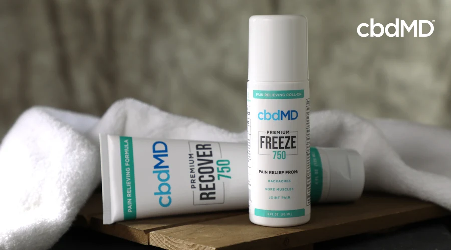 750 mg CBD Recover and 750 mg CBD Freeze sit on a wooden bench near a white towel