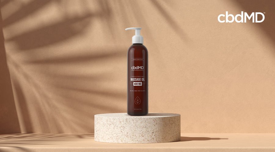 A bottle of cbd massage oil from cbdmd sits on a small stone plinth