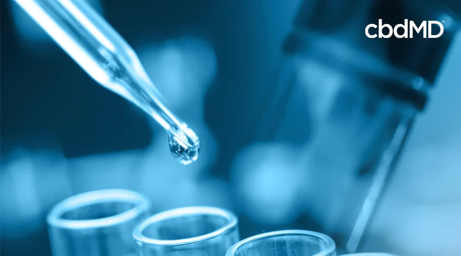 A predominantly blue image shows a dropper gently dropping liquid into flasks