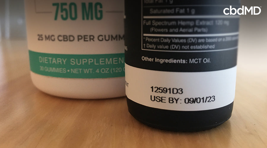 CBD gummies next to cbd oil showing the expiration date on the back - cbdMD