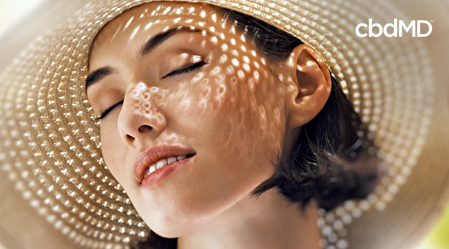 An attractive woman in a hat keeps the sun off of her head