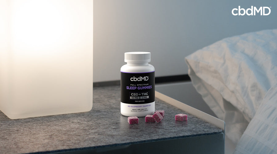 Full spectrum sleep gummies 50 mg cbd 2 mg thc raspberry on a nightstand in a bedroom - cbdMD