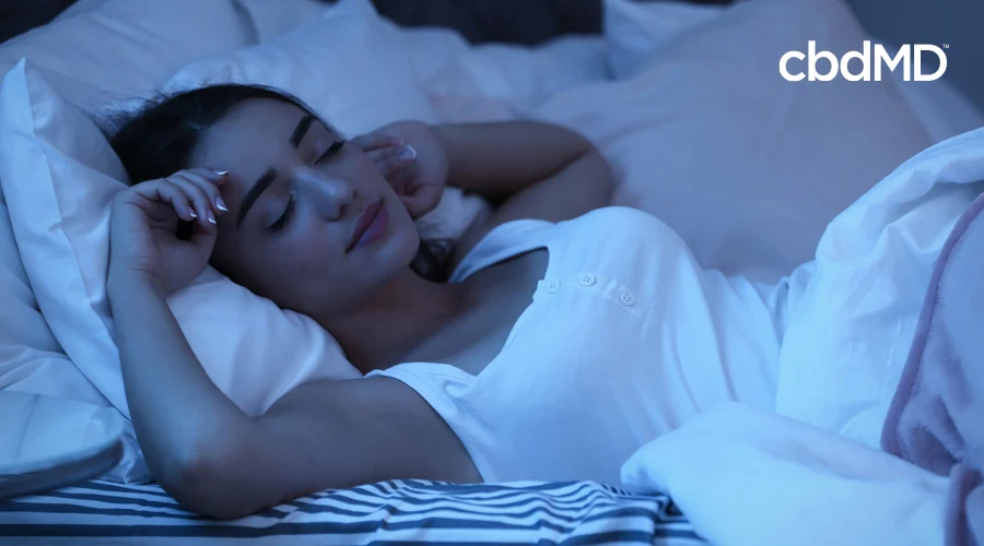 A young woman sleeps soundly in a relaxed position under fluffy white covers