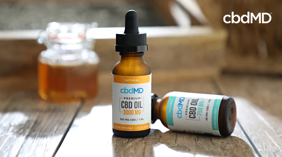 2 bottles of cbd oil tincture from cbdmd sit on a wooden table