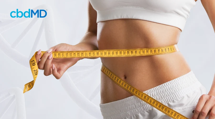 An athletic woman in white measures her bare mid-drift with a yellow tape measure