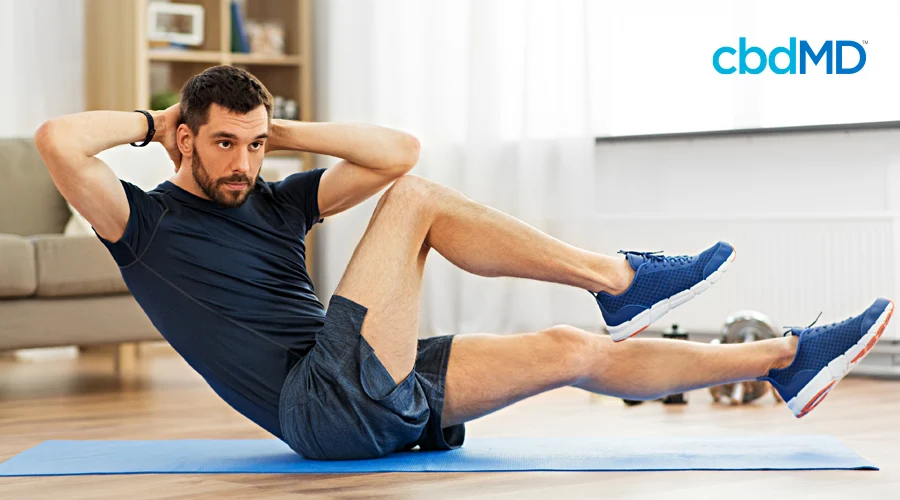 A man looks at his computer as he does exercises on the floor