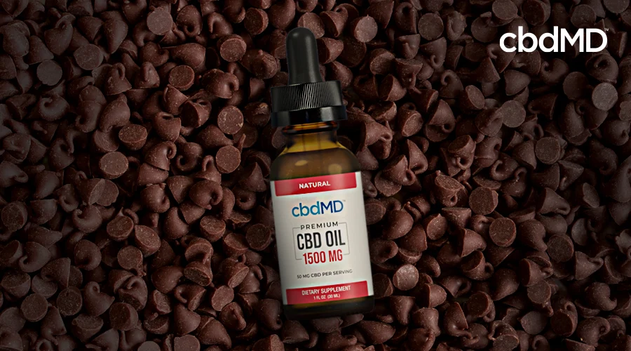 A 1500 mg bottle of cbd oil tincture from cbdmd sits among a pile of chocolate chips