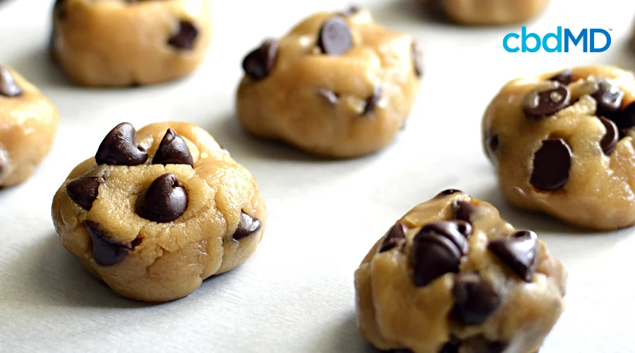 Several cbd chocolate chip cookies sit on a baking sheet ready to be baked