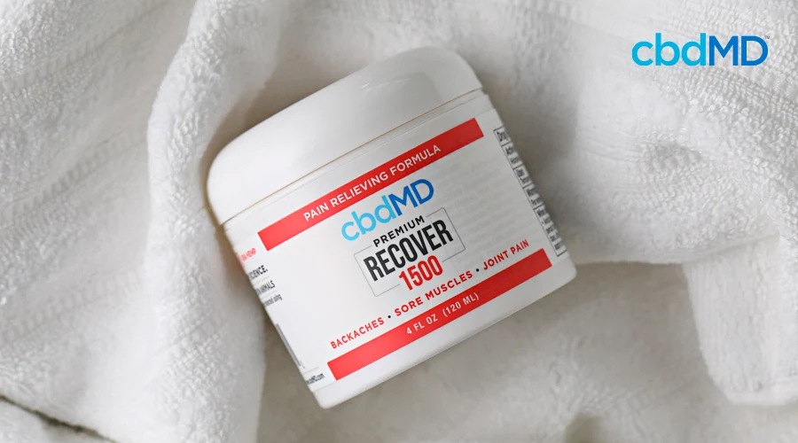 A tub of cbd recover from cbdmd sits on a white towel