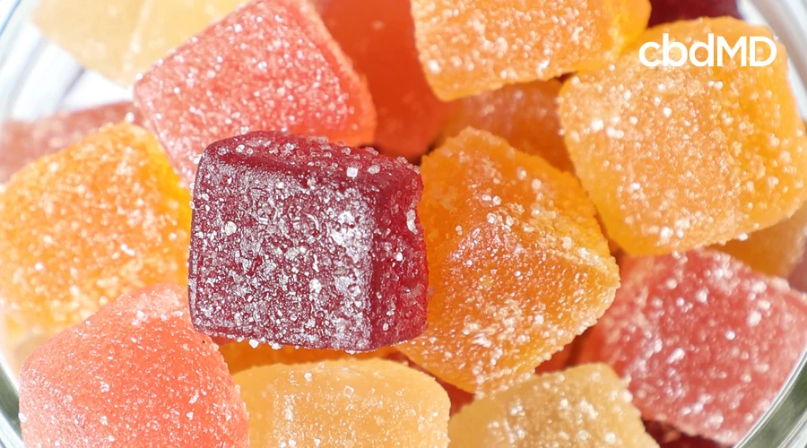 Up-close image of orange, red, and pink CBD gummies stacked on top of each other