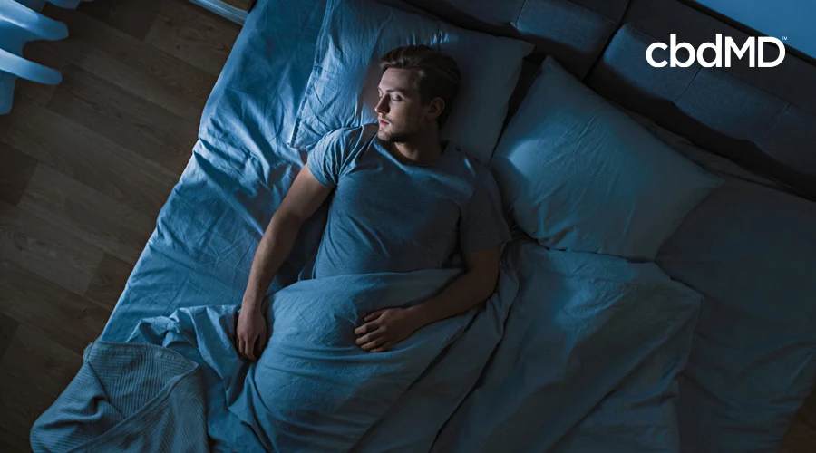 A man sleeps in a bed beneath fluffy covers