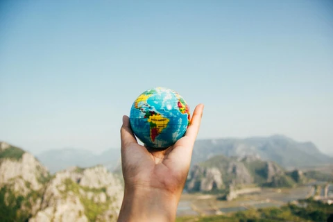 Man Holding World Globe Facing Mountain