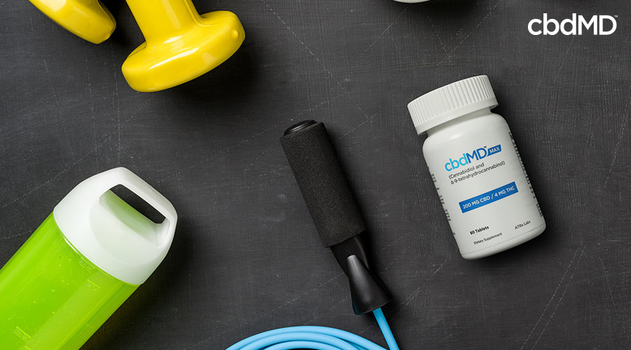 A water bottle dumbbells and a jump rope next to max for pain tablets - cbdMD