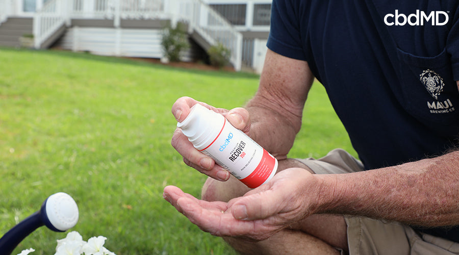 A man outside holding cbd recover cream in his hand - cbdMD