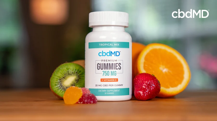 A bottle of 750 mg cbd gummies from cbdmd sits on a table near some fruit