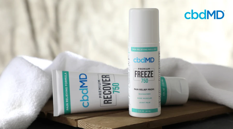 A tube and pump bottle of 750 mg CBD Freeze from cbdmd sit a wooden bench with a white towel