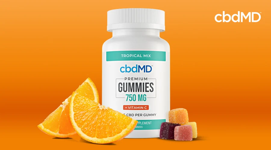 A bottle of vitamin c gummies from cbdmd sits next to orange slices