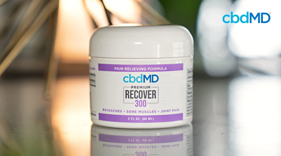 A jar of 300 mg cbd recover from cbdmd sits on a reflective surface