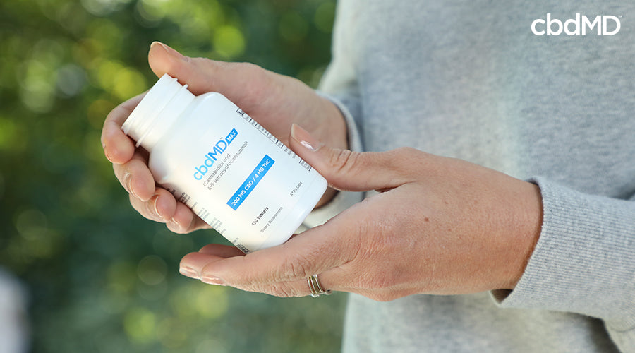 A woman holding max for pain 200 mg cbd 4 mg thc tablets in her hands - cbdMD