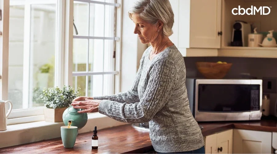 Woman Adding cbdMD CBD Tincture to Tea
