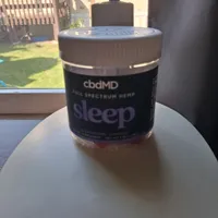 Customer-uploaded image. Click to see more details. The image represents: A jar of cbdMD full spectrum hemp sleep product sitting on a white plate on a table, with a window and backyard visible in the background.