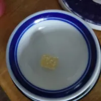 Customer-uploaded image. Click to see more details. The image represents: A white bowl with blue rim containing a small amount of yellow liquid or oil in the center