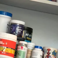 Customer-uploaded image. Click to see more details. The image represents: A bathroom shelf or cabinet displaying various personal care and health products including protein powders, supplements, and grooming items in containers and jars of different sizes and colors.